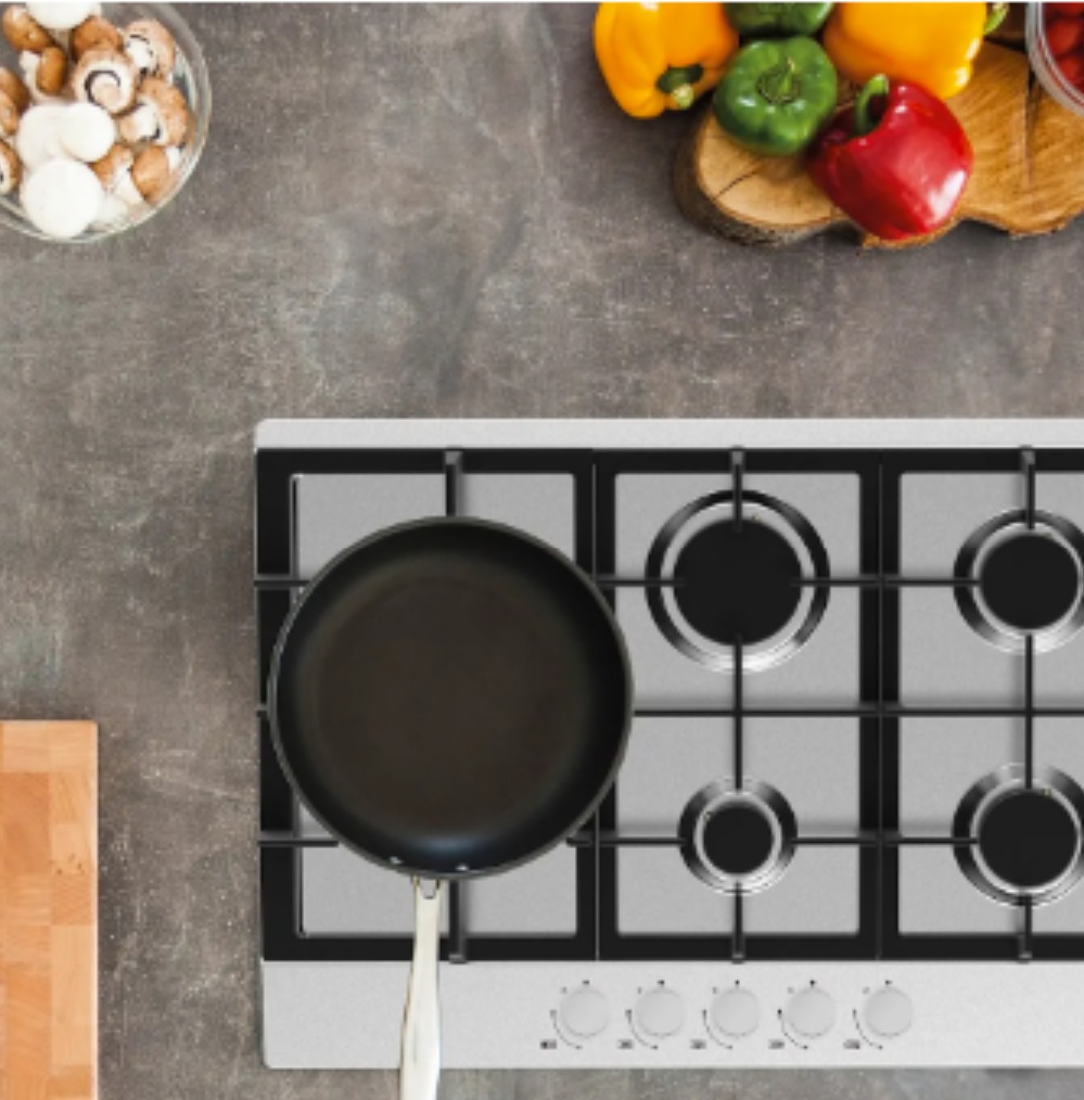 Gas hob with frying pan and chopped vegetables.